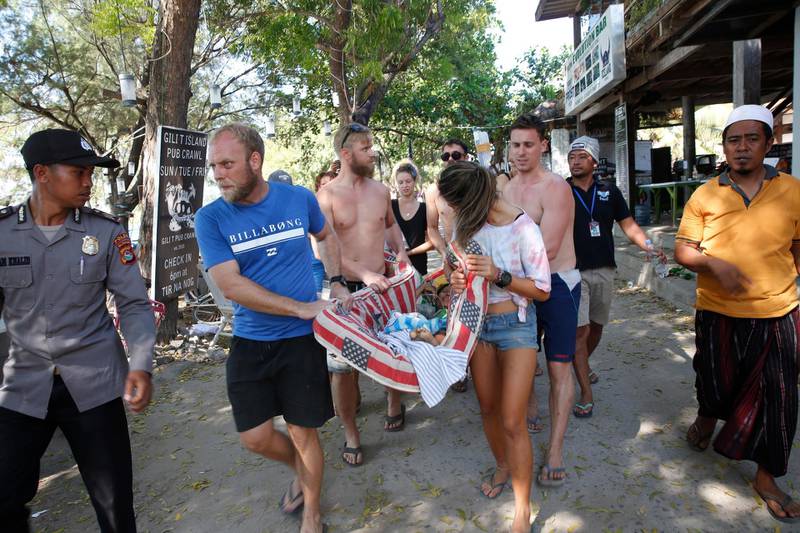 Foreign tourists help an Indonesian survivor in Gili Trawangan island.  EPA