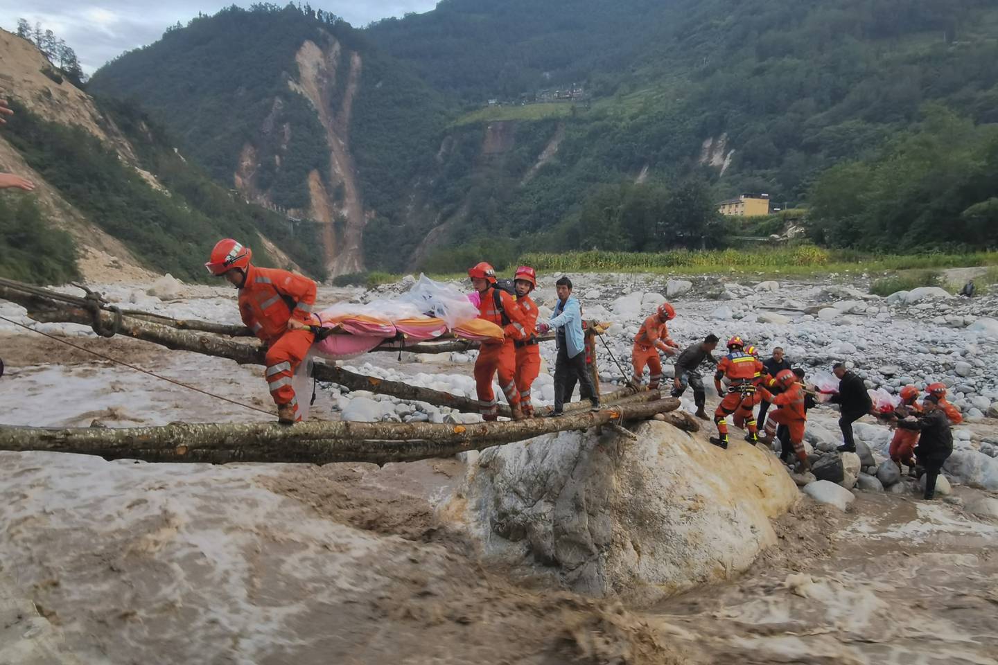 Rescuers carry survivors across a river on the outskirts of Moxi, a town in China's Sichuan province, after an earthquake hit on Monday. AP