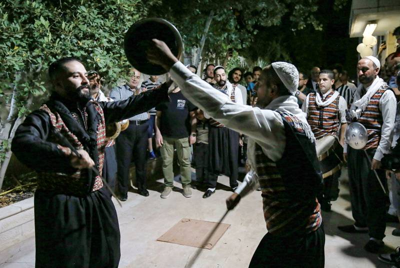 Syrian "Arada" folklore dancers of the "Bab al-Hara" troupe perform while in traditional garb during a celebration for the graduation of two of the sons of one of their members, Fahed Shehadeh, from universities, in Jordan's capital Amman on June 24, 2022.  - Although the centuries-old "Arada" dance is traditionally performed at weddings, its popularity has seen its songs modified to fit various celebrations.  A troupe typically consists of 10 to 20 dancers wearing traditional attire of loose-fitting black trousers, white cotton shirts, embroidered vests,  white skullcaps and a shawl wrapped around the waist.  Swords and decorative shields are worn and the dance culminates in members spinning their swords in the air before engaging in ceremonial sword play.  (Photo by Khalil MAZRAAWI  /  AFP)