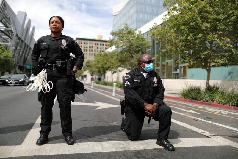 A police officer kneels during a protest against the death in Minneapolis police custody of George Floyd, outside LAPD headquarters in Los Angeles, California. Reuters