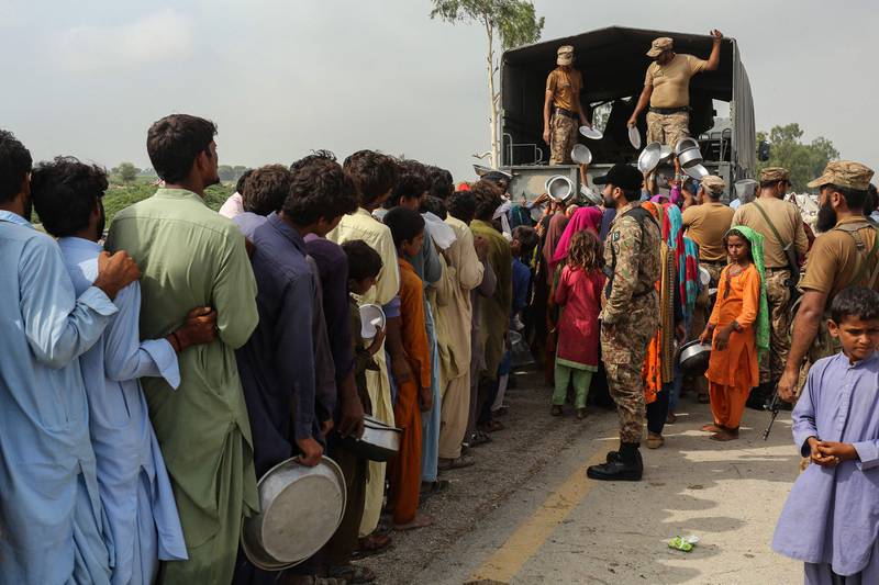 Soldiers distribute food to people affected by floods, near a makeshift camp in Rajanpur. AFP