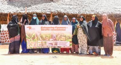 Women from a farmers group posing with a conflict resolution banner