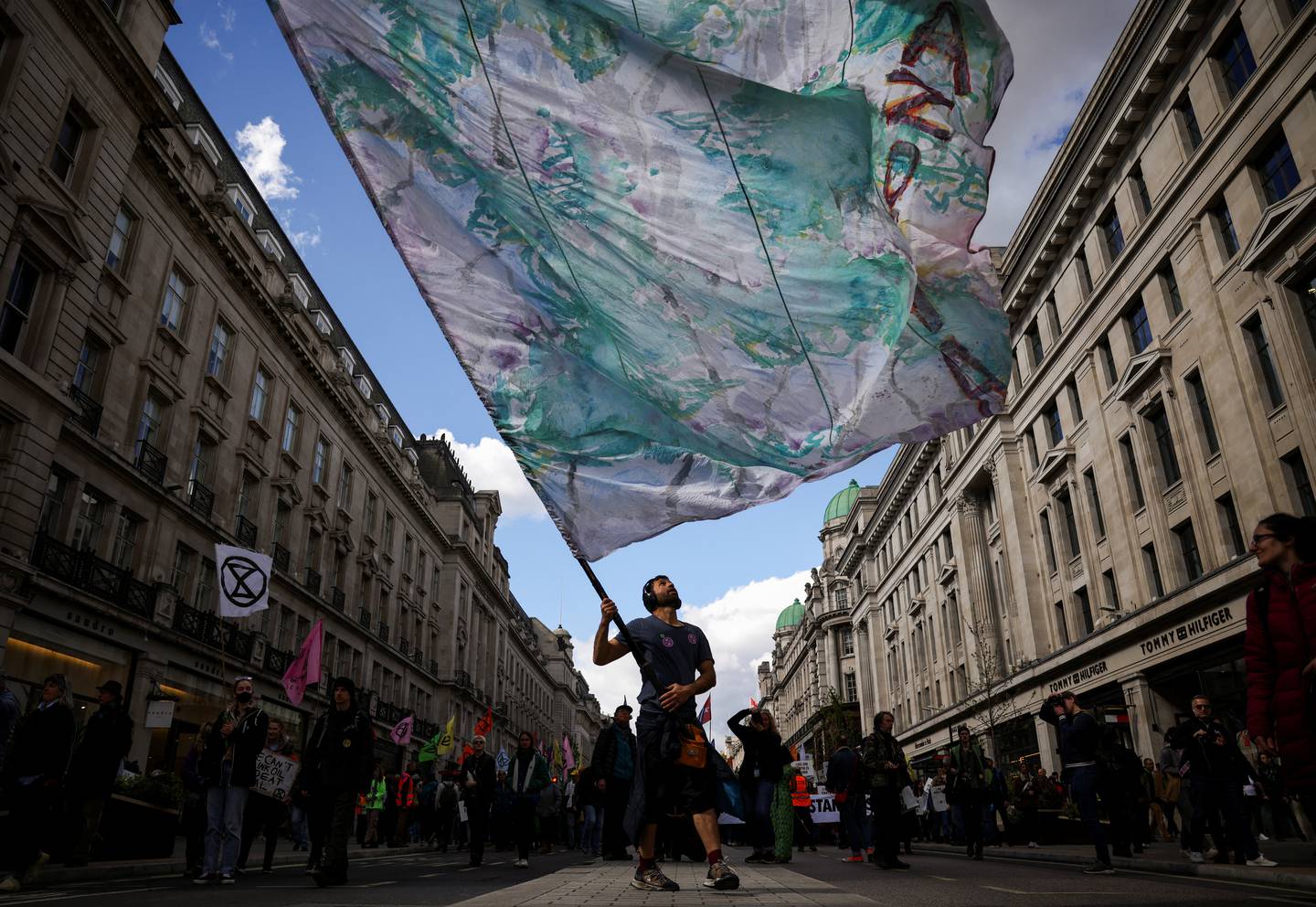 A man holds up a flag as climate activists from Extinction Rebellion take part in a demonstration at Oxford Circus. Reuters.