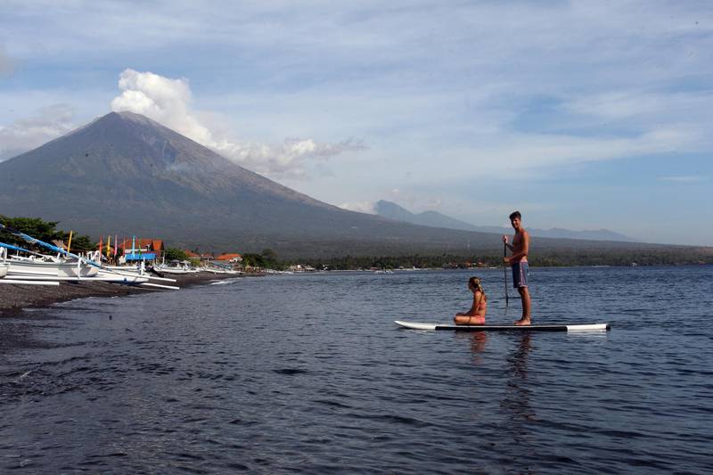 Tourists paddle their board as they watch Mount Agung spew ash and smoke in Karangasem, Bali, Indonesia. Firdia Lisnawati / AP Photo