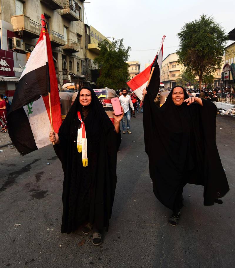 Iraqi women carry the Iraqi national flag shortly after the resignation of Iraqi Prime Minister Adel Abdel-Mahdi, as they take part in the ongoing protests at the Al Tahrir square in central Baghdad.  EPA