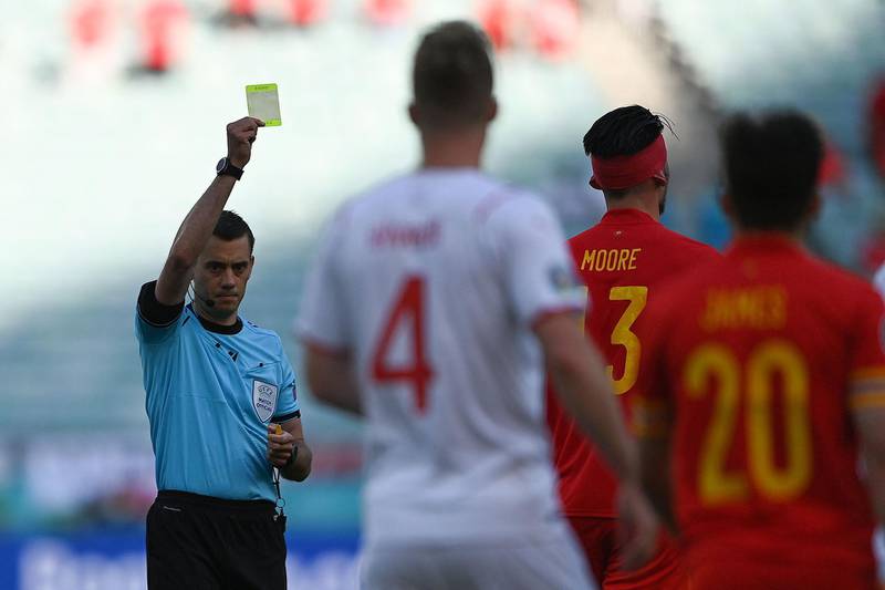 Referee Clement Turpin shows yellow card to Wales' midfielder Kieffer Moore. AFP