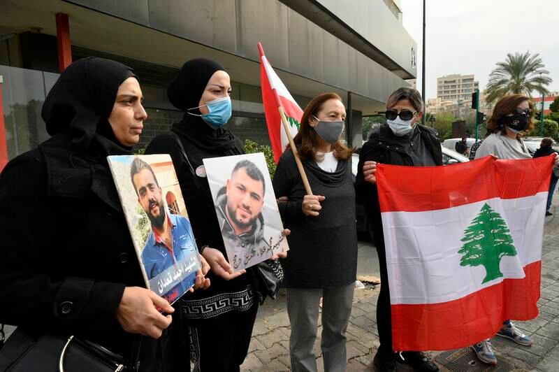 Anti-government protesters and families of Beirut Blast victims carry portraits of the deceased relatives and a national flag to support the public prosecutor Judge Tarek Bitar during a parliament session in Beirut, Lebanon, December 7. EPA