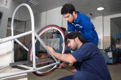 Driver Khalifa Ali Ahmad Awadh, kneeling, and the lead builder Humaid Al Araidi, the lead builder, work on the vehicle that the HCT Dubai are entering for the eco-friendly car competition. Courtesy of HCT