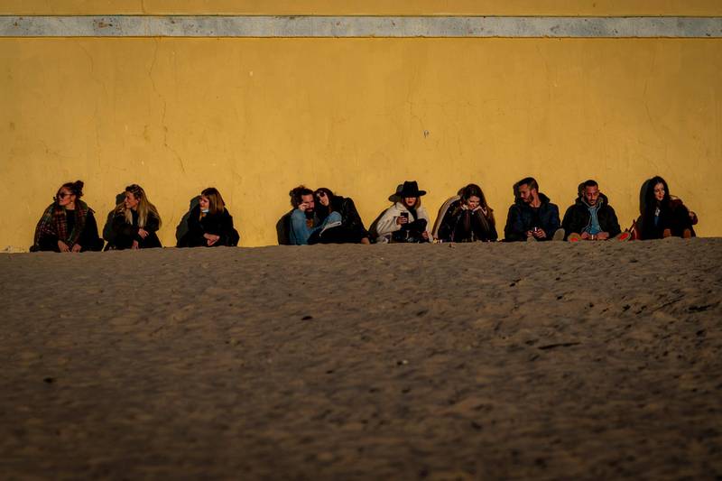 People sit as they look at the sunset on a beach at the city of Cadiz in Andalucia, Southern Spain. AP Photo
