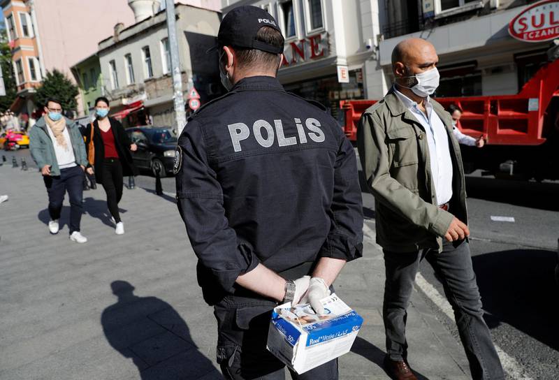 A police officer holding a box of protective face masks checks if people wear them, as the coronavirus disease outbreak continues, in Istanbul, Turkey. Reuters