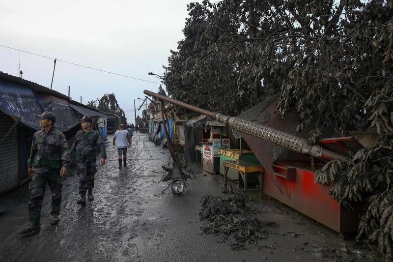 Policemen walk past a damaged post after a volcano eruption in Talisay, Batangas. EPA