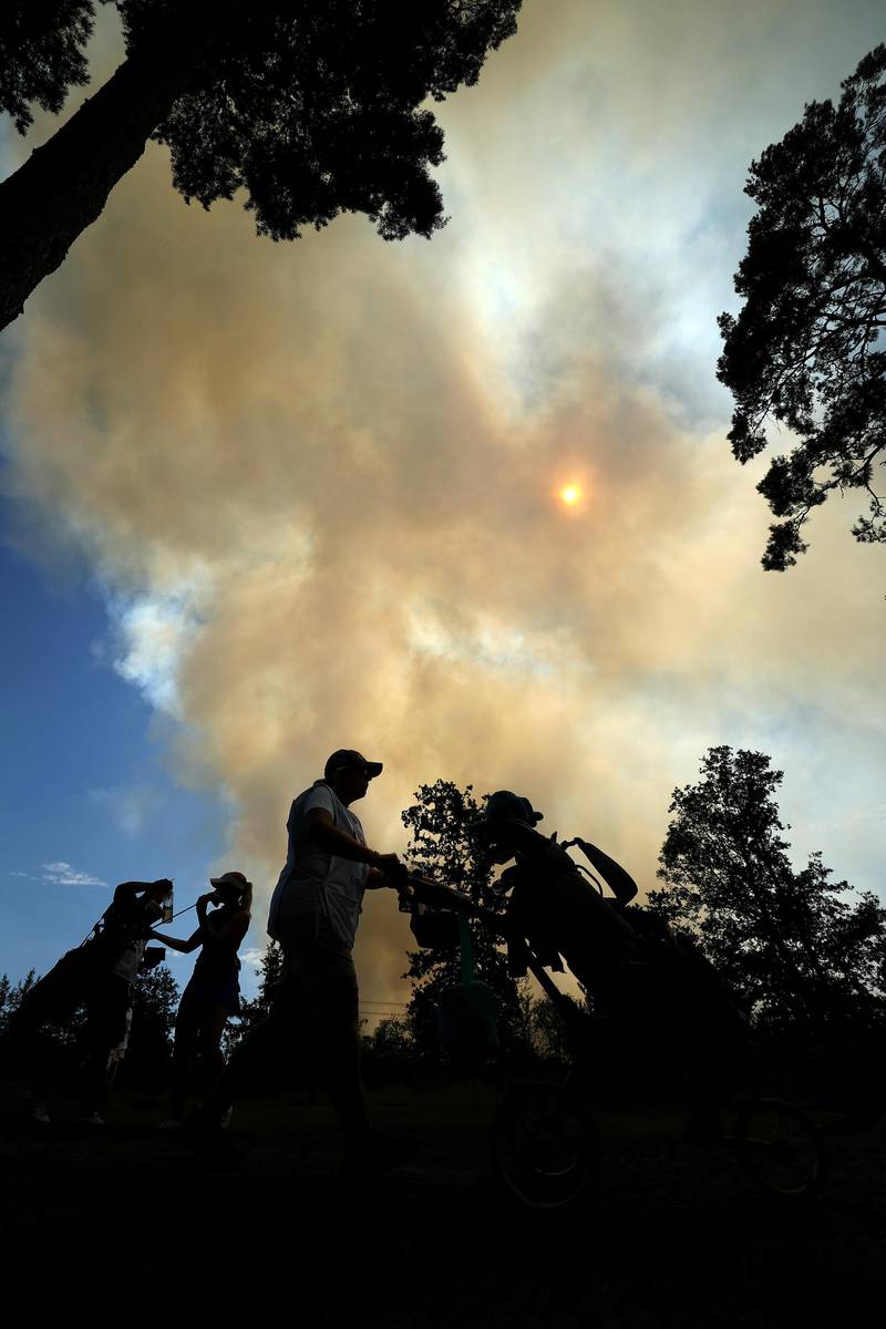 Players walk on the 10th hole as large fire on nearby Chobham Common during Day 3 of the Rose Ladies Series at Wentworth Golf Club on Friday August 7. Getty