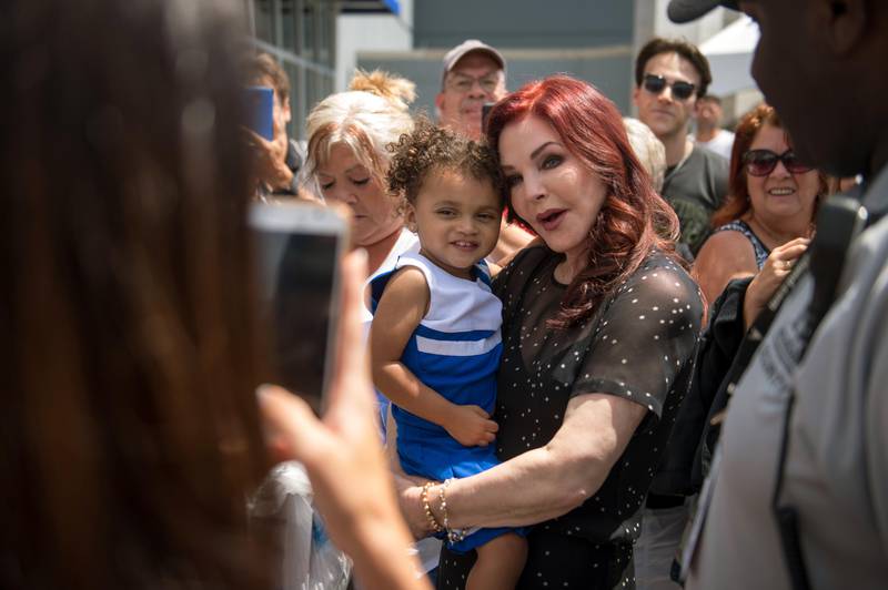 Priscilla Presley, center right, former wife of Elvis Presley, holds a child while greeting fans at Elvis Presley's Memphis near Graceland, Elvis Presley's Memphis home, on Tuesday, Aug. 15, 2017, in Memphis, Tenn. Fans from around the world are at Graceland for the 40th anniversary of his death. Presley died August 16, 1977. Brandon Dill / AP photo