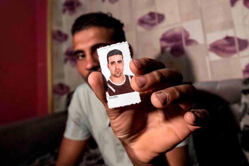 Egyptian Karim Farrag displays a picture of his brother Mohamed, one of 17 Egyptians that went missing in Libya while trying to get to Europe, during an interview at the Dahmasha village in the Sharkia governorate, 60Km northeast of the capital, on September 23, 2020. Thousands of desperate migrants bound for Europe have perished in the Mediterranean Sea. In one impoverished Egyptian town, families fear that 15 of their sons are among the dead. / AFP / Khaled DESOUKI

