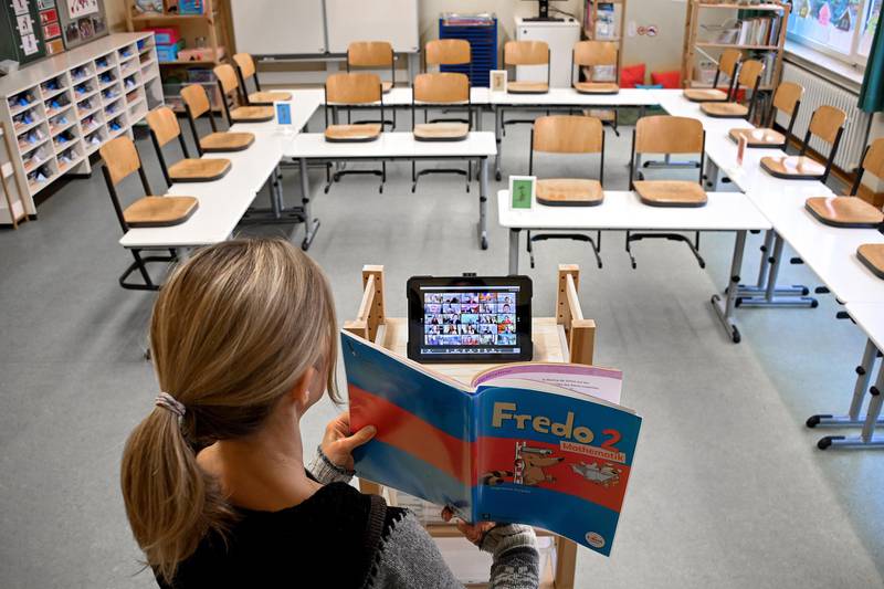 A teacher stands in an empty classroom and uses an iPad to teach children at home in Dinslaken, Germany. EPA