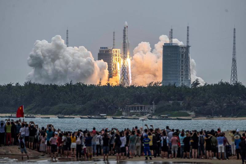 People watch a Long March 5B rocket, carrying China's Tianhe space station core module, as it lifts off from the Wenchang Space Launch Center in southern China's Hainan province on April 29, 2021. (Photo by AFP) / China OUT