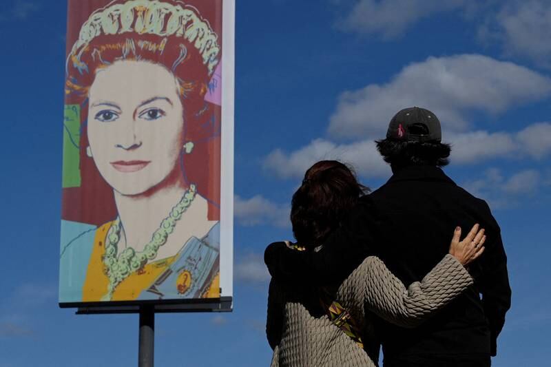 A couple look at an image of Britain's Queen Elizabeth II, promoting an exhibition at the Tate Modern gallery in London, Britain. Reuters