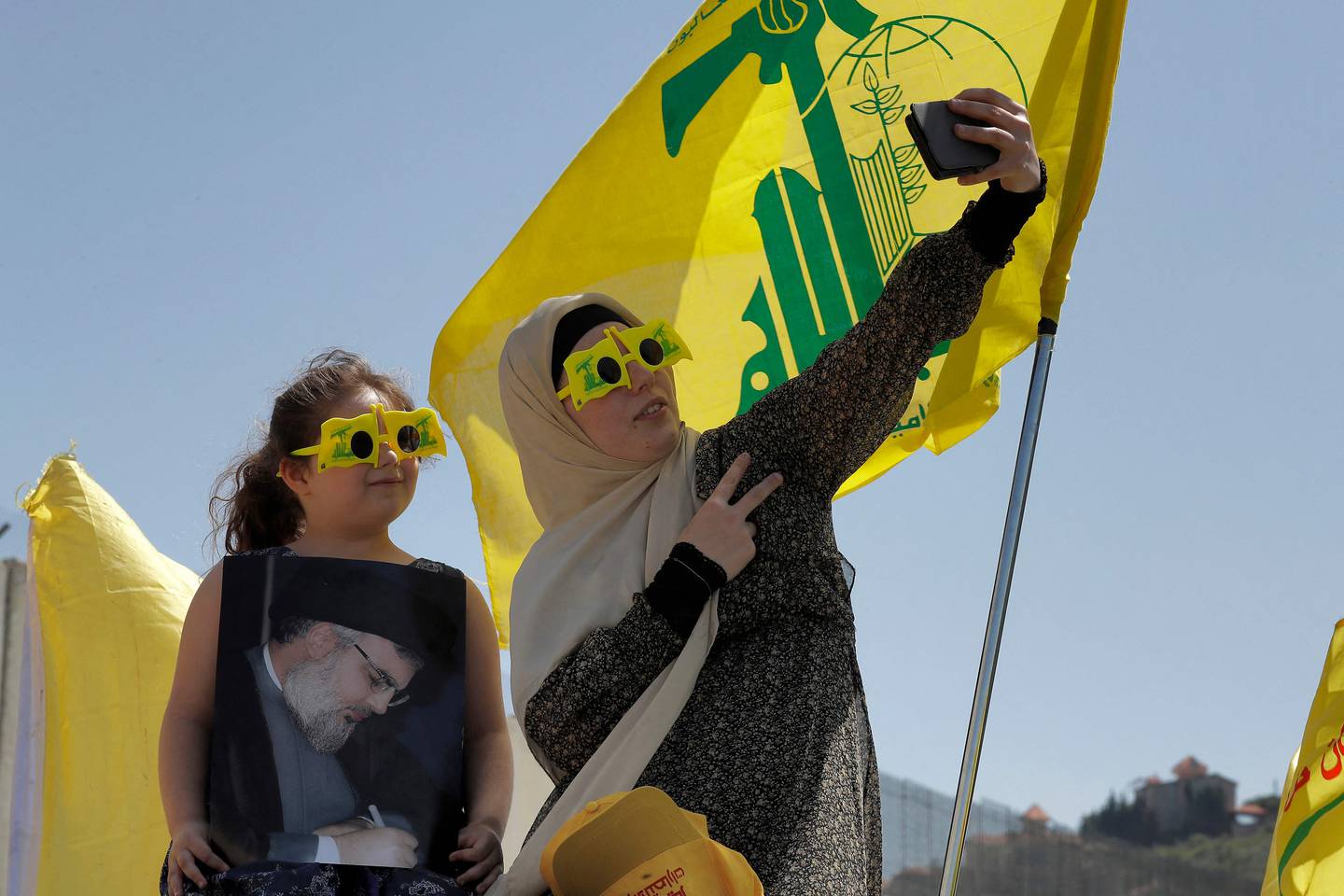 A supporter of Lebanon's Shiite Muslim Hezbollah movement poses for a selfie with a child and the group's flags in Lebanon's southern town of Kfar Kila on May 25. AFP