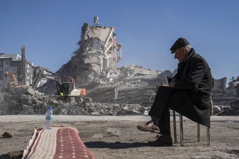 A man takes a seat as debris is removed from a collapsed building where five of his family members are trapped in Nurdagi, south-eastern Turkey. AP
