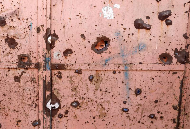 Pupils peep through shrapnel holes in the school gate. AFP