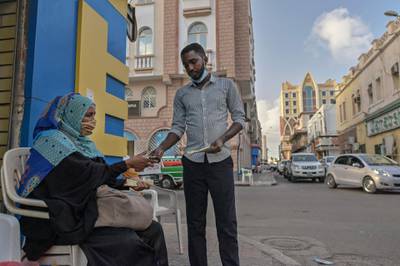 Noura Hassan (L) offers Djiboutian francs in exchange for US dollars offered by a client at a street corner where she sits cradling a satchel filled with a variety of regional and international currencies, waiting on customers to come by for foreign exchange (Forex) services in Djibouti's capital on April 11, 2021.  When her husband died a decade ago, the mother-of-three started out with just her savings in francs, before acquiring more currencies.
Every day, Hassan refers to a printout from the local bank to gauge exchange rates and determines what to offer customers for the major currencies.
 / AFP / TONY KARUMBA
