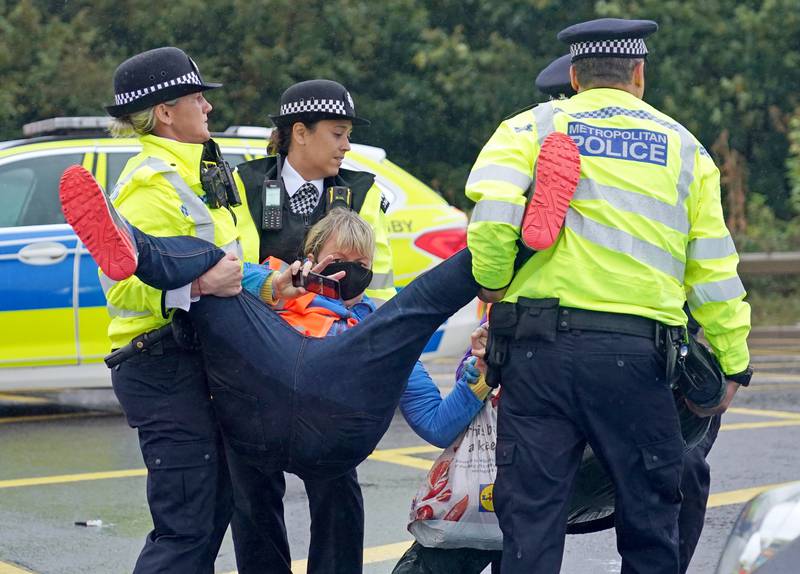 UK police detain a protester from Insulate Britain occupying a road leading to Heathrow Airport. The activists want the government to insulate and retrofit homes to cut climate emissions. All photos: PA