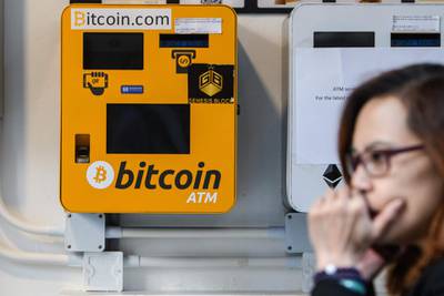 (FILES) In this file photo taken on December 18, 2017 A woman uses her phone as she walks past an ATM machine for digital currency Bitcoin in Hong Kong on December 18, 2017.   From its birth in an anonymous paper in 2008 to growth into one of the world's most volatile and closely watched financial instruments in 2018, bitcoin has lived through a tumultuous first 10 years. / AFP / Anthony WALLACE
