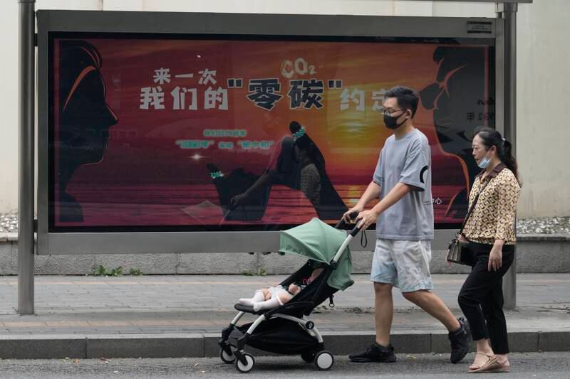 Beijing residents pass by a government poster with the words 'Our Carbon Zero Agreement'. AP