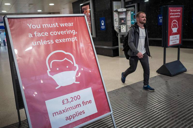 A man, not wearing a face covering, passes signs telling travellers they must wear face mask unless they are exempt, as he leaves Victoria station during the evening 'rush hour' in central London on September 23, 2020. The UK on Wednesday reported 6,178 new coronavirus cases, a marked jump in the daily infection rate that comes a day after Prime Minister Boris Johnson unveiled new nationwide restrictions. / AFP / Tolga AKMEN
