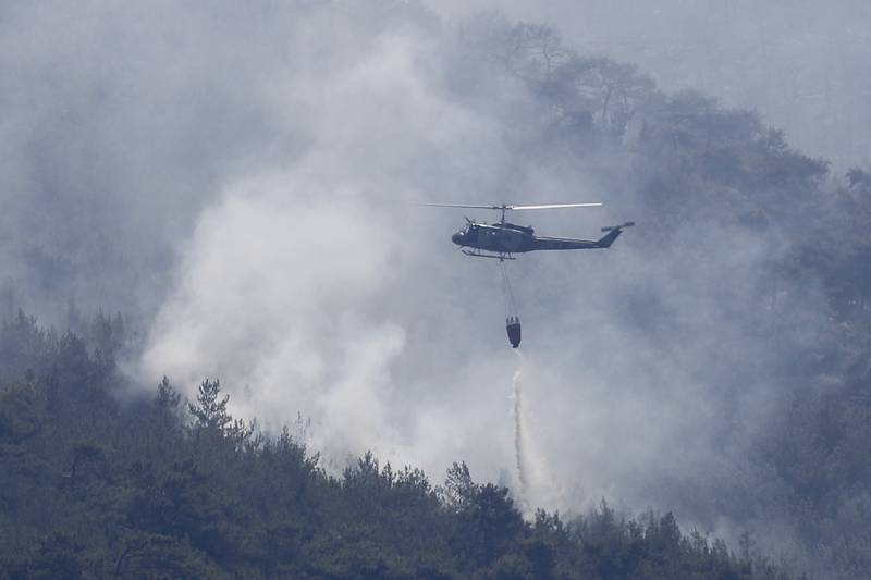 A Lebanese army helicopter drops water over a forest fire, at Qobayat village, in the northern Akkar province, Lebanon, Thursday, July 29, 2021.  Lebanese firefighters are struggling for the second day to contain wildfires in the country's north that have spread across the border into Syria, civil defense officials in both countries said Thursday.  (AP Photo / Hussein Malla)