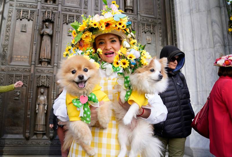 A woman poses with her two dogs during the annual Easter Parade and Bonnet Festival on Fifth Avenue in New York. AFP