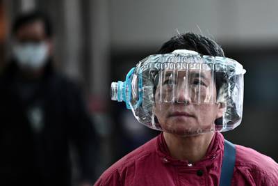 A woman wears a plastic water bottle with a cutout to cover her face, as she walks on a footbridge in Hong Kong on January 31, 2020, as a preventative measure following a virus outbreak which began in the Chinese city of Wuhan. - The World Health Organization, which initially downplayed the severity of a disease that has now killed 170 nationwide, warned all governments to be "on alert" as it weighed whether to declare a global health emergency. (Photo by Anthony WALLACE / AFP)