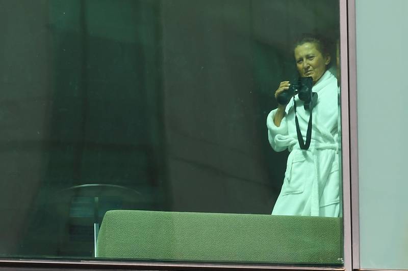 A lady is seen with binoculars in a hotel room at Crown Promenade Hotel in Melbourne. Travellers and Australian residents who arrive into the country from overseas are being sent straight to makeshift quarantine facilities across Australia, and will spend 14 days of quarantine in state-funded hotel rooms, with doors guarded by state police, defence personnel or private security guards.  EPA