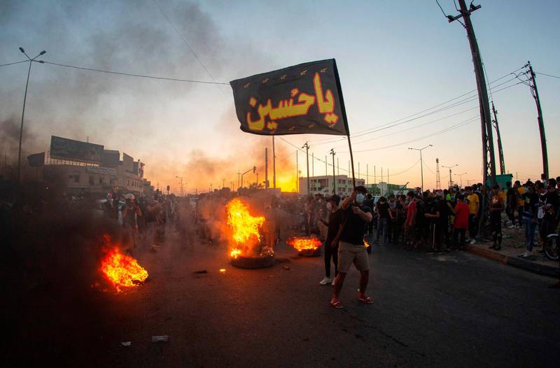 Iraqi demonstrators gather near burning tyres during a protest near the governor's residence in the southern city of Basra.  AFP