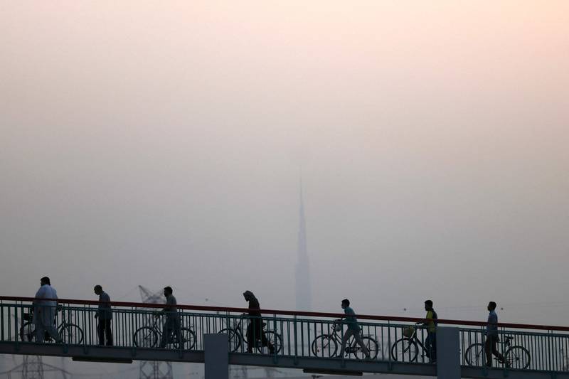 Cyclists cross a bridge in Dubai on a dusty and humid June day. Karim Sahib / AFP