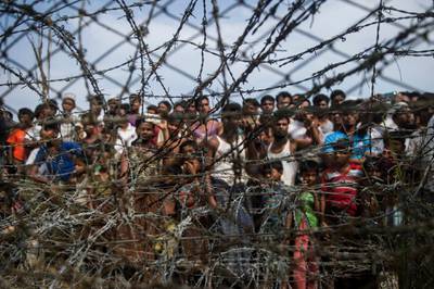 (FILES) In this file photo taken on April 25, 2018, taken from Maungdaw district, Myanmar's Rakhine state on April 25, 2018 shows Rohingya refugees gathering behind a barbed-wire fence in a temporary settlement setup in a "no man's land" border zone between Myanmar and Bangladesh. Around 600,000 Rohingya Muslims remaining in Myanmar face a "serious risk of genocide", UN investigators said on September 16, 2019, warning the repatriation of a million of the minority already driven out of the country by the army remains "impossible". / AFP / Ye Aung THU
