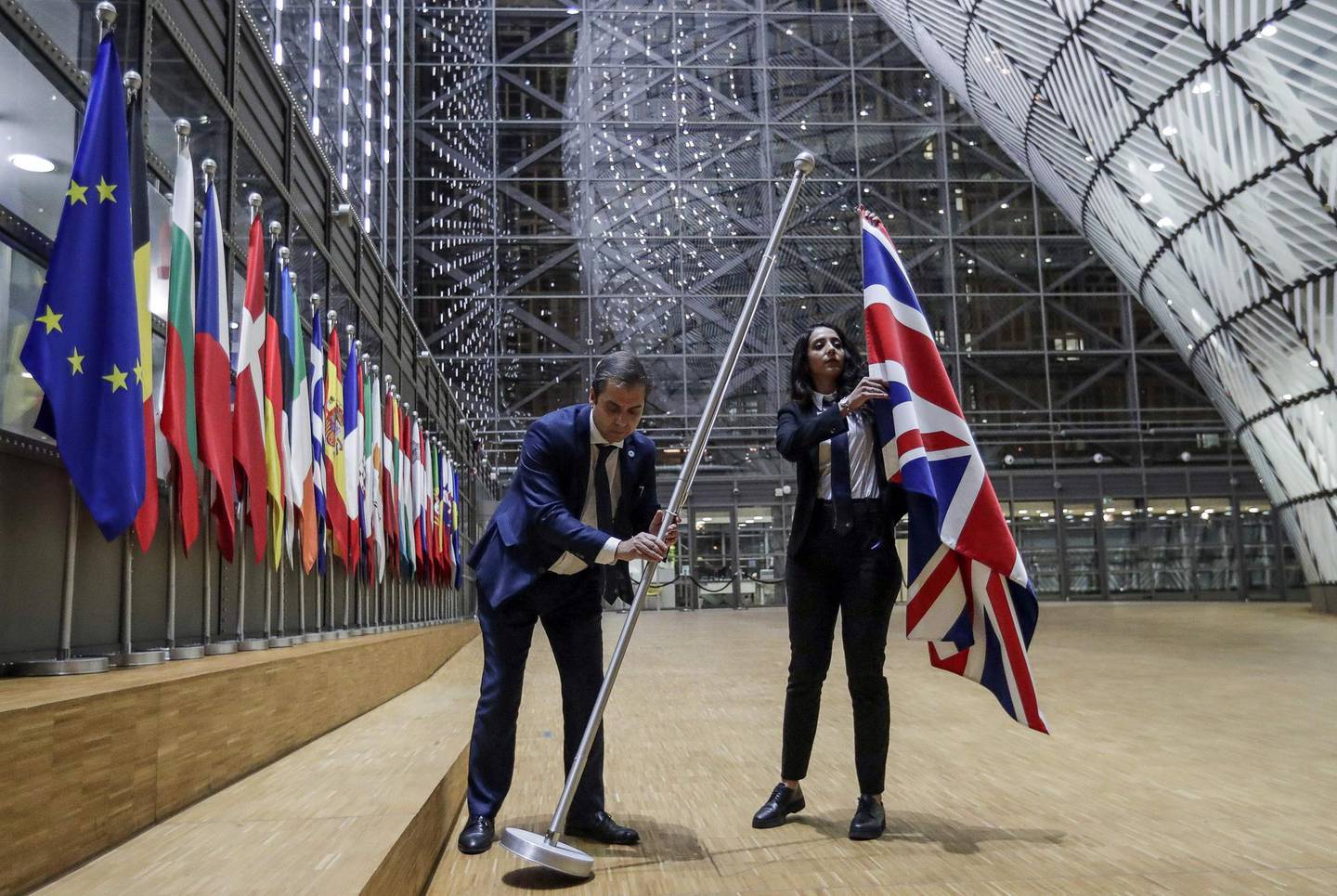 TOPSHOT - EU Council staff members remove the United Kingdom's flag from the European Council building in Brussels on Brexit Day, January 31, 2020. Britain leaves the European Union at 2300 GMT on January 31, 2020, 43 months after the country voted in a June 2016 referendum to leave the block. The withdrawal from the union ends more than four decades of economic, political and legal integration with its closest neighbours. / AFP / POOL / OLIVIER HOSLET
