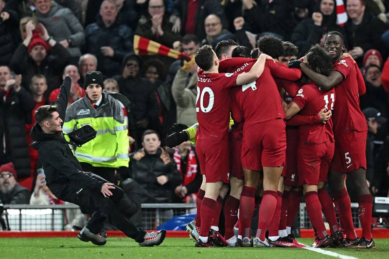 A pitch invader slides into a group of Liverpool players celebrating their seventh goal against Manchester United in a league match at Anfield. AFP