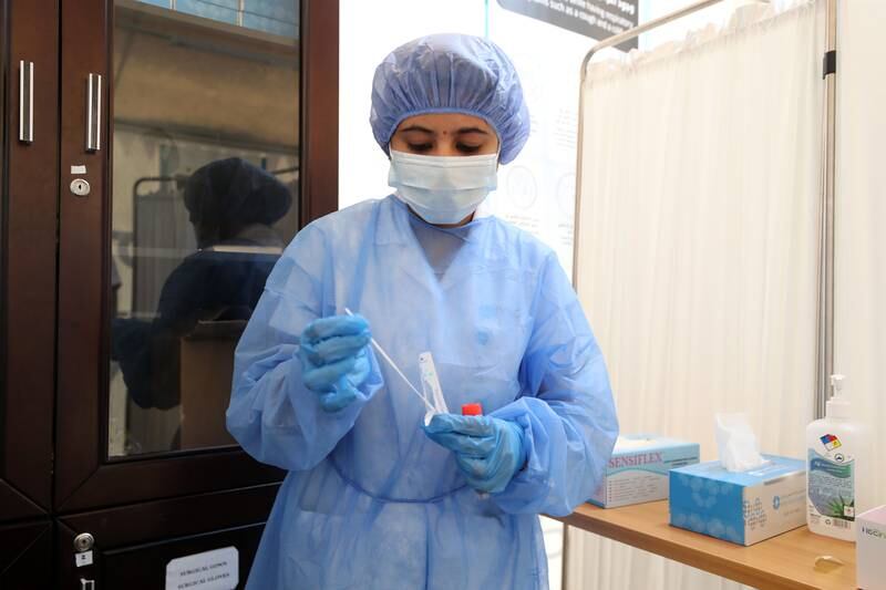 A member of staff at The Royal NMC hospital in Sharjah prepares to take a sample to test for Covid-19. Chris Whiteoak / The National