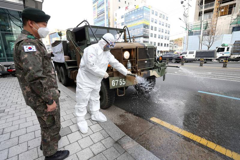 A South Korean soldier wearing a protective suit sprays disinfectant to prevent the spread of the COVID-19 on a street in Daegu, South Korea.  AP