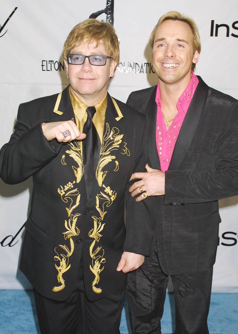 Elton John, in a black suit with gold embellishment and a gold shirt, and David Furnish arrive at the Elton John post-Oscars party on March 25, 2001 at Moomba restaurant in West Hollywood. Getty Images
