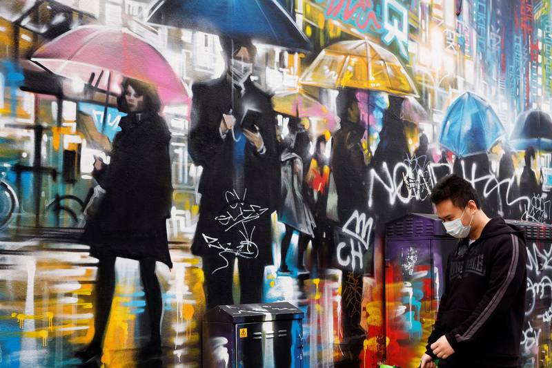A man wearing a face mask walks past graffiti in London. Reuters