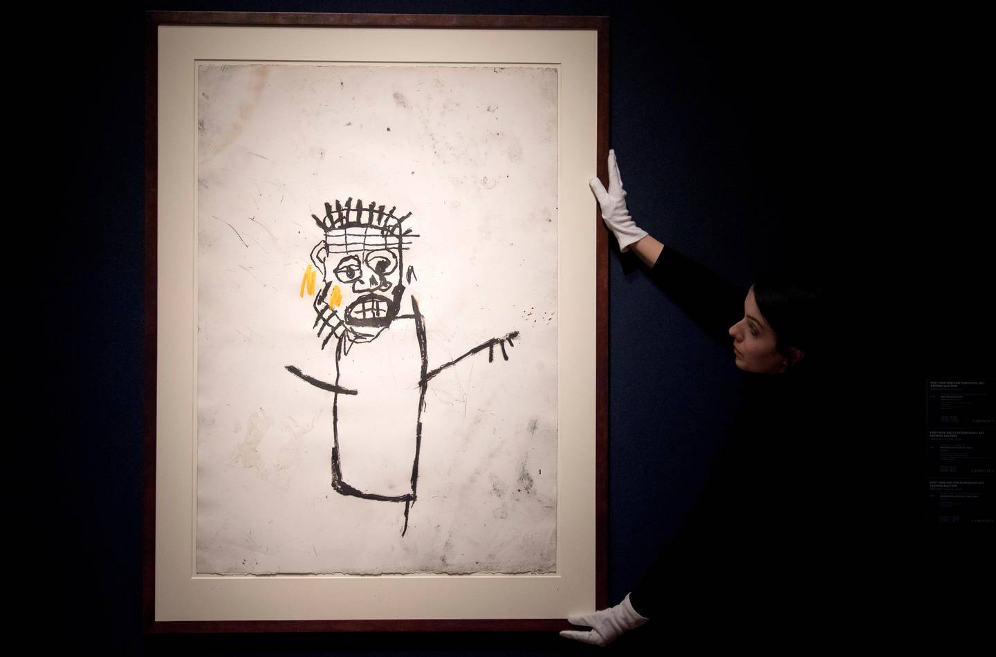 An employee poses with an artwork by American artist Jean-Michel Basquiat entitled "Untitled", with an estimated value of 1-1.5 million GBP (1.2-1.7 million EUR: 1.2-1.8 million USD) during a photocall ahead of the Post-War and Contemporary art sale at Christie's in London on March 3, 2017.