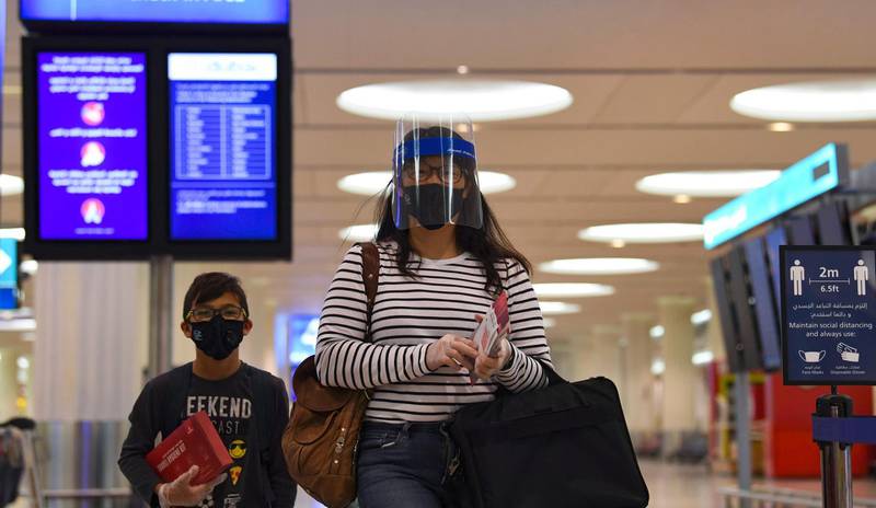 Passengers of an Emirates airlines flight, departing to the Australian city of Sydney, wear protective gear at Dubai International Airport on May 22, 2020, after the resumption of scheduled operations by the Emirati carrier, amid the ongoing novel coronavirus pandemic crisis.




  / AFP / Karim SAHIB

