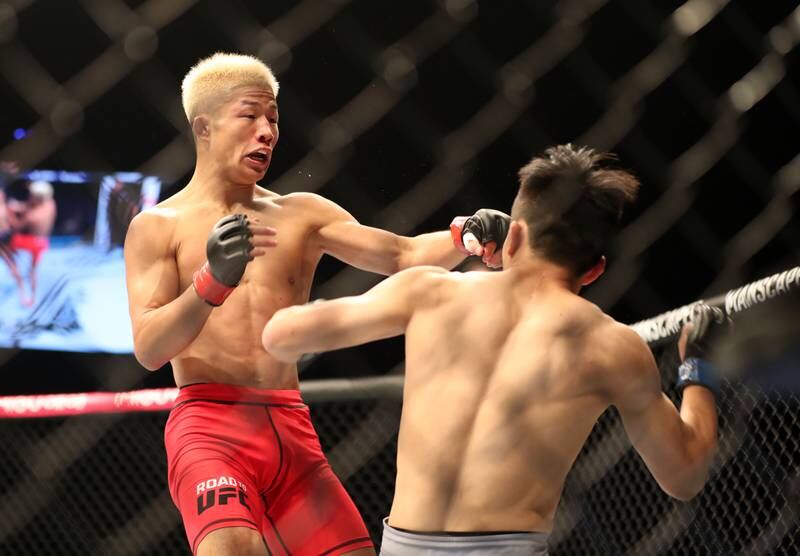 Rina Nakamura, red, punches Shohei Nose in their bantamweight bout of Road to UFC in Abu Dhabi. Chris Whiteoak / The National