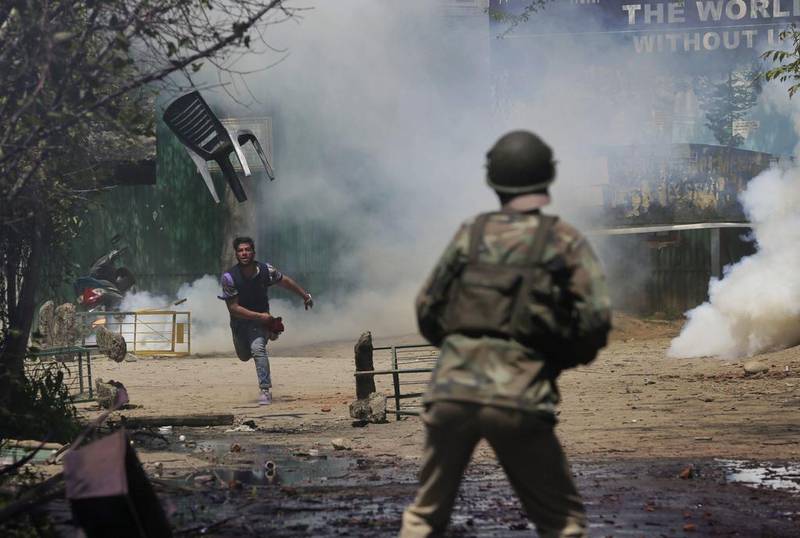 A Kashmiri student throws a chair on Indian policemen as they clash in Srinagar, Indian controlled Kashmir. The clashes began in Srinagar when hundreds of college students took to the streets to protest a police raid in a college in southern Pulwama town over the weekend, in which at least 50 students were injured. Mukhtar Khan / AP Photo