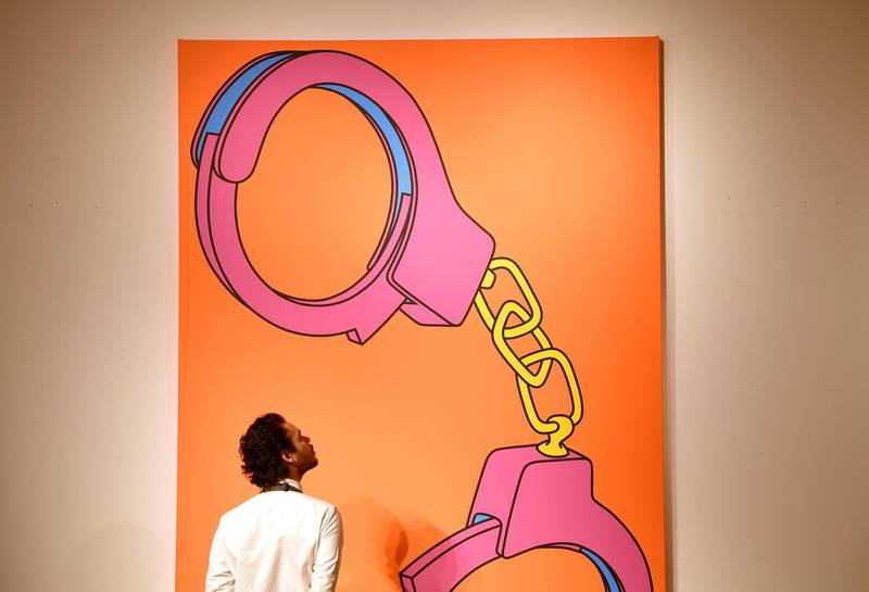 An employee poses as he views 'Handcuffs' by Michael Craig-Martin ahead of the George Michael Collection online auction at Christie's in London, Britain, March 8, 2019. REUTERS/Toby Melville