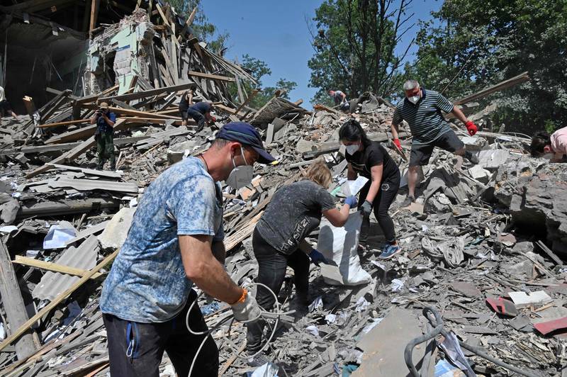 Railway workers and local residents dismantle the ruins of a building hit by a Russian rocket near Kharkiv, Ukraine. AFP