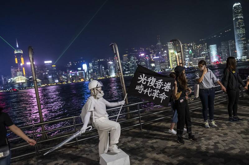 A living statue dressed as the Lady Liberty Hong Kong statue and demonstrators wearing face masks form a human chain during the Face Mask Way event in the Tsim Sha Tsui district of Hong Kong, China. Bloomberg