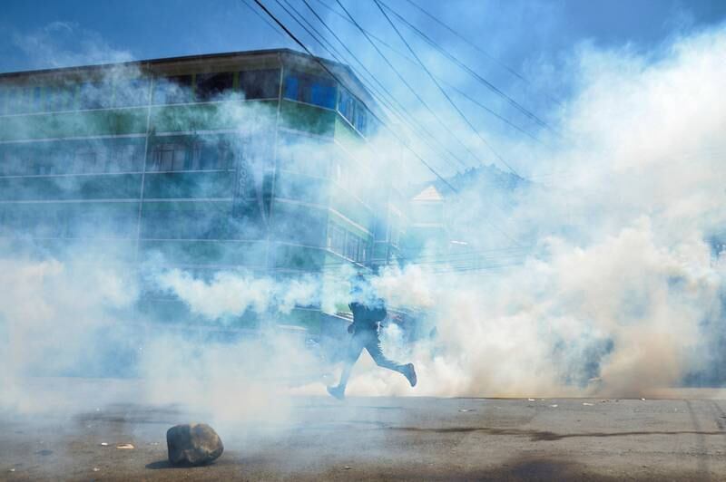 A demonstrator runs through tear gas during clashes between coca growers and police over a new coca market, in La Paz, Bolivia. Reuters
